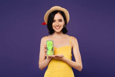 mor izole en iyi alışveriş uygulaması ile akıllı telefon tutan hasır şapka gülümseyen güzel kız 