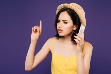 saman şapka üzgün güzel kız parmak ile işaret ve mor izole akıllı telefon konuşuyor 