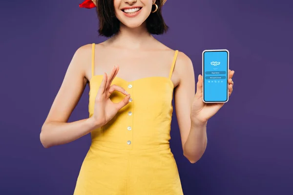 乌克兰 2019年7月3日 微笑的女孩在拿着智能手机与Skype标志和显示确定标志隔离紫色裁剪视图 — 图库照片