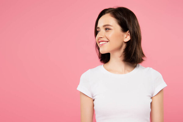 smiling pretty girl looking away isolated on pink