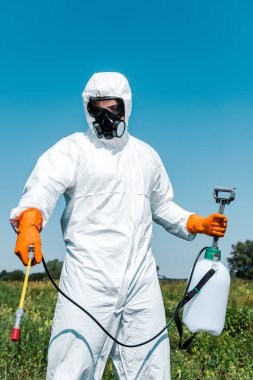 exterminator in latex gloves and white uniform holding spray outside  clipart