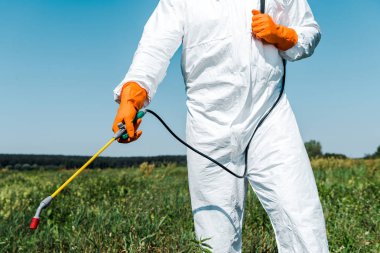cropped view of exterminator in latex gloves and white uniform holding spray outside  clipart