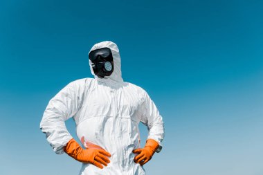 exterminator in protective mask and uniform standing with hands on hips  clipart