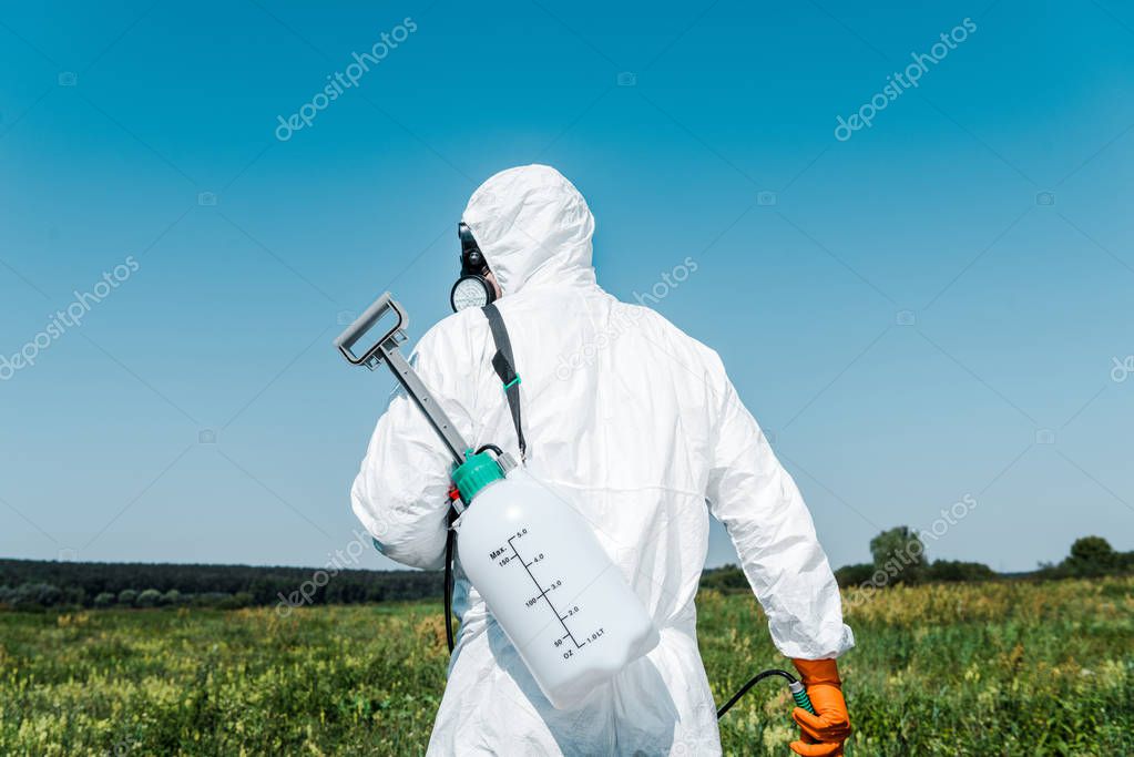 exterminator in white uniform with toxic spray outside 