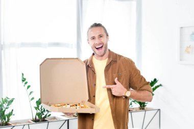 yakışıklı ve gülümseyen işadamı ofiste pizza ile kutuya parmak ile işaret 