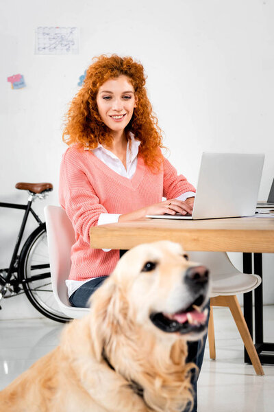 selective focus of woman smiling and looking at golden retriever
