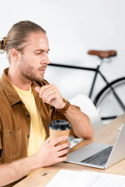 Homem Pensativo Bonito Segurando Copo Papel Olhando Para Laptop — Fotografia de Stock