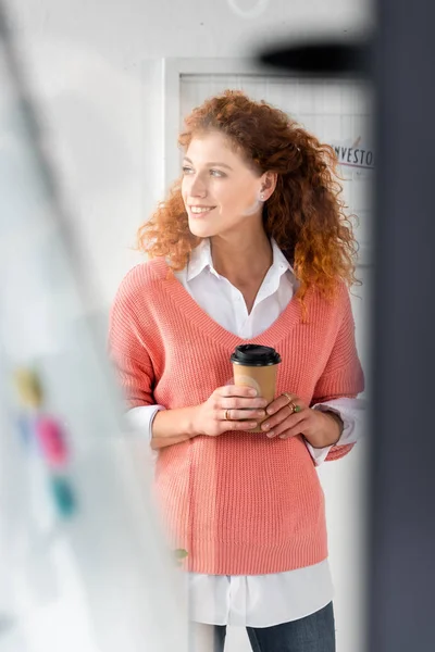 ピンクのセーターで魅力的で笑顔のビジネスウーマンの選択的な焦点は 紙のカップを保持します — ストック写真