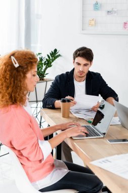 dizüstü bilgisayar kullanarak ve ofiste evrak yapıyor iki arkadaş 