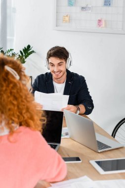 dizüstü bilgisayar kullanarak kulaklık gülümseyen ve yakışıklı adam seçici odak 