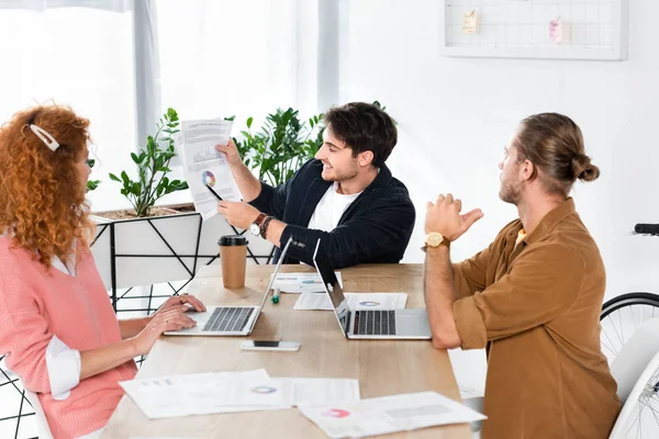 Hombre Guapo Mostrando Papel Con Gráficos Gráficos Sus Amigos — Foto de Stock