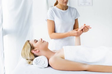 cropped view of masseur doing hand massage to attractive woman  clipart