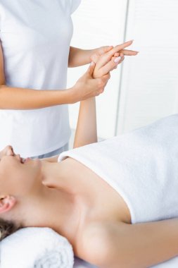 cropped view of masseur doing hand massage to smiling woman  clipart