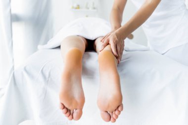 spa kadına ayak masajı yapan masör kırpılmış görünümü 