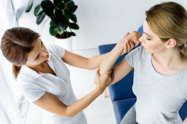 klinikte gri t-shirt hastanın hastanın elini dokunan chiropractor yüksek açı görünümü 