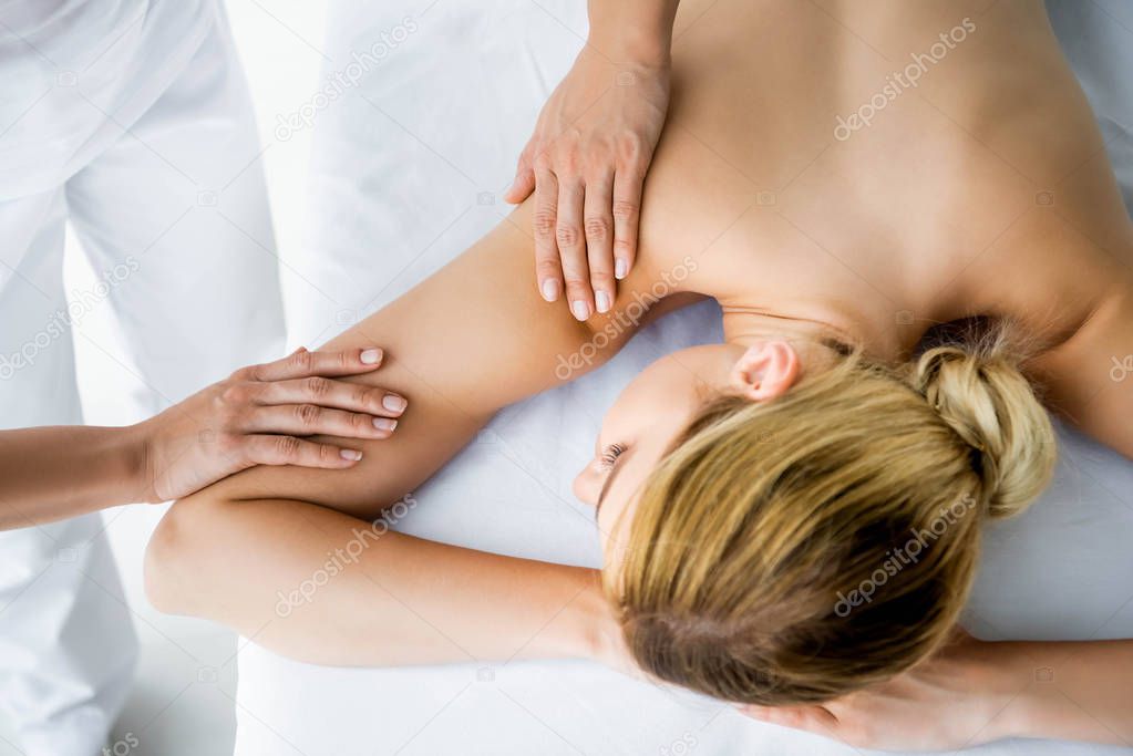 cropped view of masseur doing back massage to woman in spa 