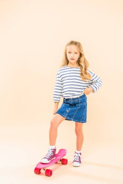 pembe kalça üzerinde el ile kaykay üzerinde duran çocuğun tam uzunlukta görünümü