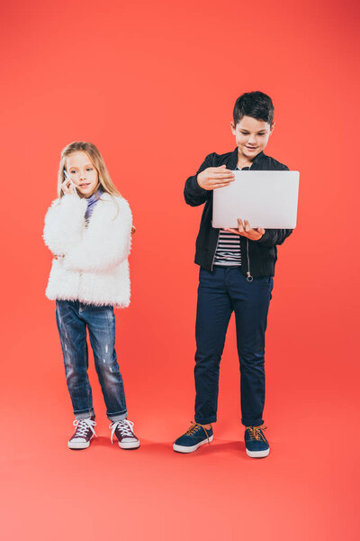 full length view of kids with smartphone and laptop on red