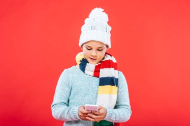 kırmızı izole akıllı telefon kullanarak kış kıyafeti çocuğun ön görünümü