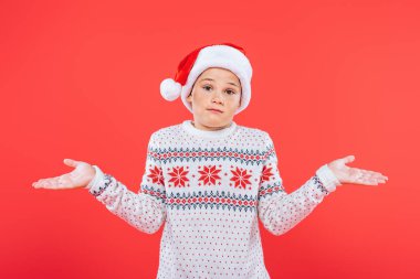 kırmızı izole omuz silkme jest gösteren kazak ve santa şapka çocuğun ön görünümü