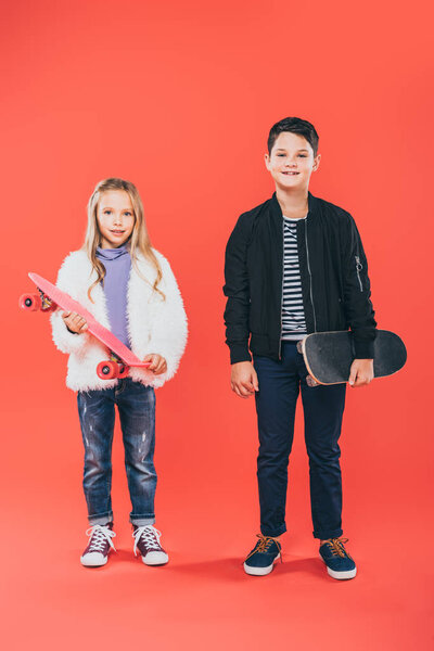 full length view of two kids with skateboards on red
