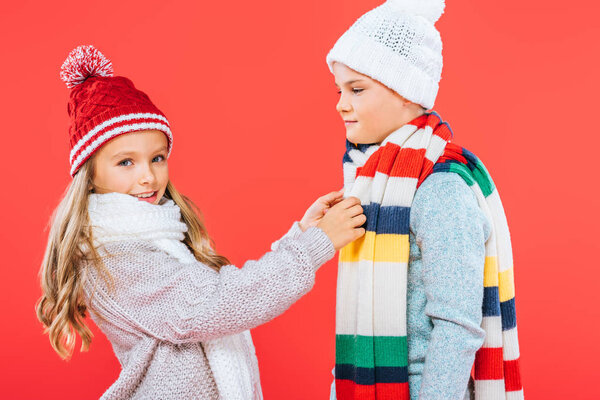 two kids in winter outfits isolated on red