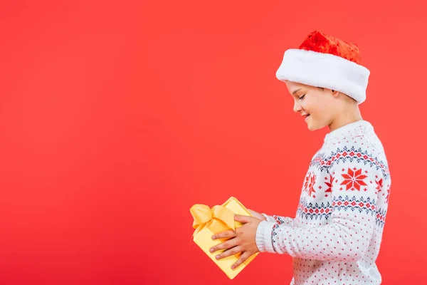 Vue Latérale Gosse Souriant Dans Exploitation Santa Chapeau Présent Isolé — Photo