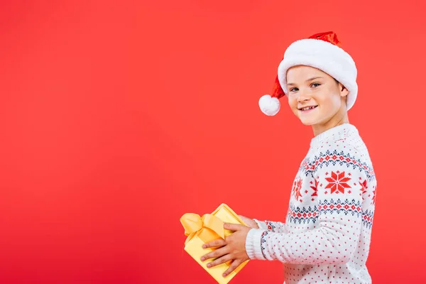 Uśmiechnięty Dzieciak Santa Hat Trzyma Prezent Białym Tle Czerwonym — Zdjęcie stockowe