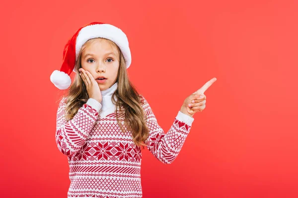 Kırmızı Izole Parmak Ile Işaret Santa Şapka Sürpriz Çocuk Görünümü — Stok fotoğraf