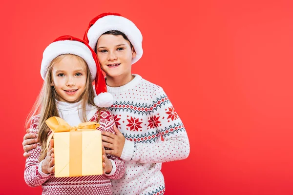 Vorderseite Der Lächelnden Kinder Weihnachtsmannmützen Mit Gegenwart Umarmung Isoliert Auf — Stockfoto