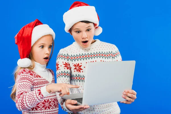 Dos Niños Sorprendidos Sombreros Santa Usando Ordenador Portátil Aislado Azul —  Fotos de Stock