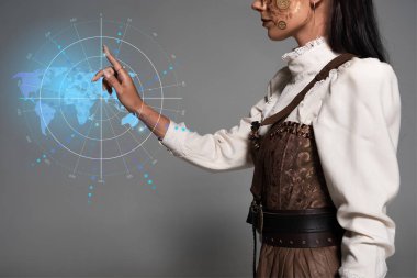 Dijital harita illüstrasyonunu işaret eden Steampunk 'lı genç kadının kırpılmış görüntüsü