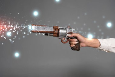 Gri renkte izole edilmiş eski model bir tabanca tutan kadın görüntüsü.