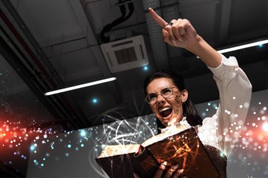 Sinirli Steampunk kadının elinde açık bir kitapla perili resimli, bağıran ve parmağıyla işaret ettiği düşük açılı bakış açısı.