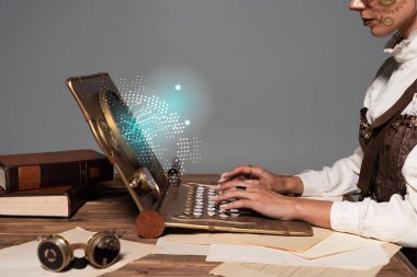 Steampunk dizüstü bilgisayarında yazı yazan bir kadının parıldayan dijital illüstrasyonunu gri masadaki izole edilmiş görüntüsü.