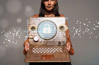 Silindir şapkalı, gözlüklü, internet güvenlik illüstrasyonlu antika dizüstü bilgisayarı gri üzerine izole edilmiş bir kadın görüntüsü.