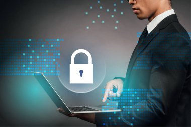 Afrika kökenli Amerikalı iş adamının karanlık arka planda internet güvenliği illüstrasyonuyla dizüstü bilgisayar kullandığına dair kısmi görüş