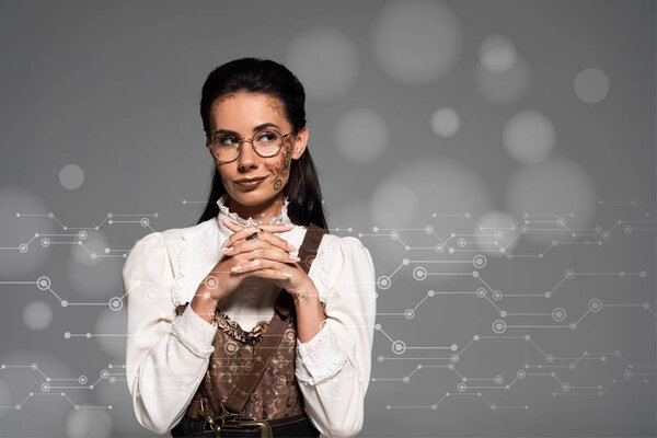 dreamy steampunk woman looking away with clenched hands near data illustration isolated on grey