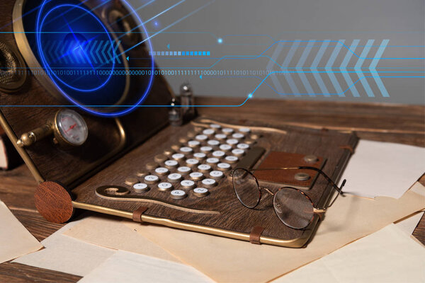 steampunk laptop with digital illustration, glasses and documents on wooden table isolated on grey