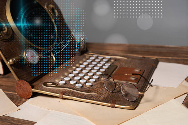 steampunk laptop with data illustration, glasses and documents on wooden table isolated on grey