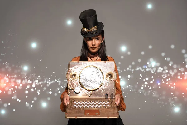 steampunk woman in top hat with goggles showing vintage laptop with glowing digital illustration isolated on grey