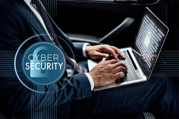 partial view of african american businessman using laptop in car with cyber security illustration