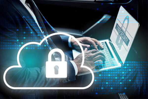 partial view of african american businessman using laptop in car with cyber security illustration