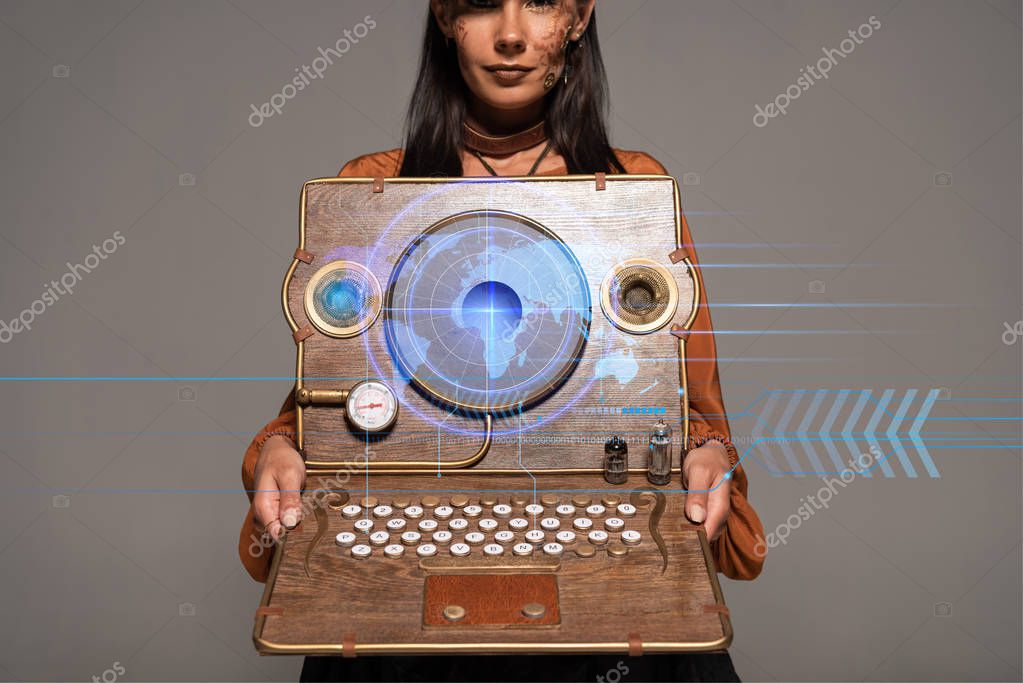 Cropped view of steampunk woman in top hat with goggles showing vintage laptop with digital map isolated on grey