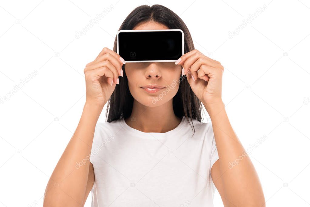 woman covering eyes while holding smartphone with blank screen isolated on white 
