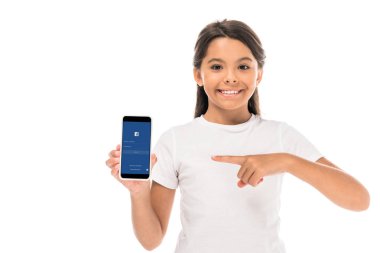 Kyiv, Ukrayna - 3 Eylül 2019: beyaz ekranda izole edilmiş Facebook uygulamalı akıllı telefonu işaret eden mutlu çocuk 