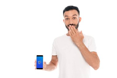 Kyiv, Ukrayna - 3 Eylül 2019: Ağzı örten ve ekranda shazam uygulamalı akıllı telefon tutan şaşırmış adam beyaz ekranda izole edildi 