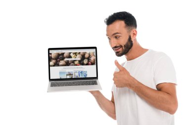 Kyiv, Ukrayna - 3 Eylül 2019: Mutlu sakallı adam başparmağını gösteriyor ve ekranda depozitolu fotoğraf web sitesine bakıyor. 