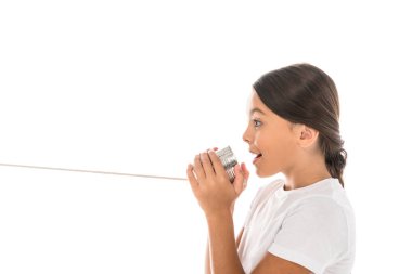 side view of happy kid holding tin can while talking isolated on white  clipart