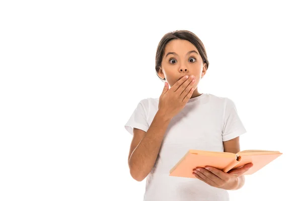 Zaskoczony Dzieciak Obejmujące Usta Podczas Gospodarstwa Książki Izolowane Białym — Zdjęcie stockowe